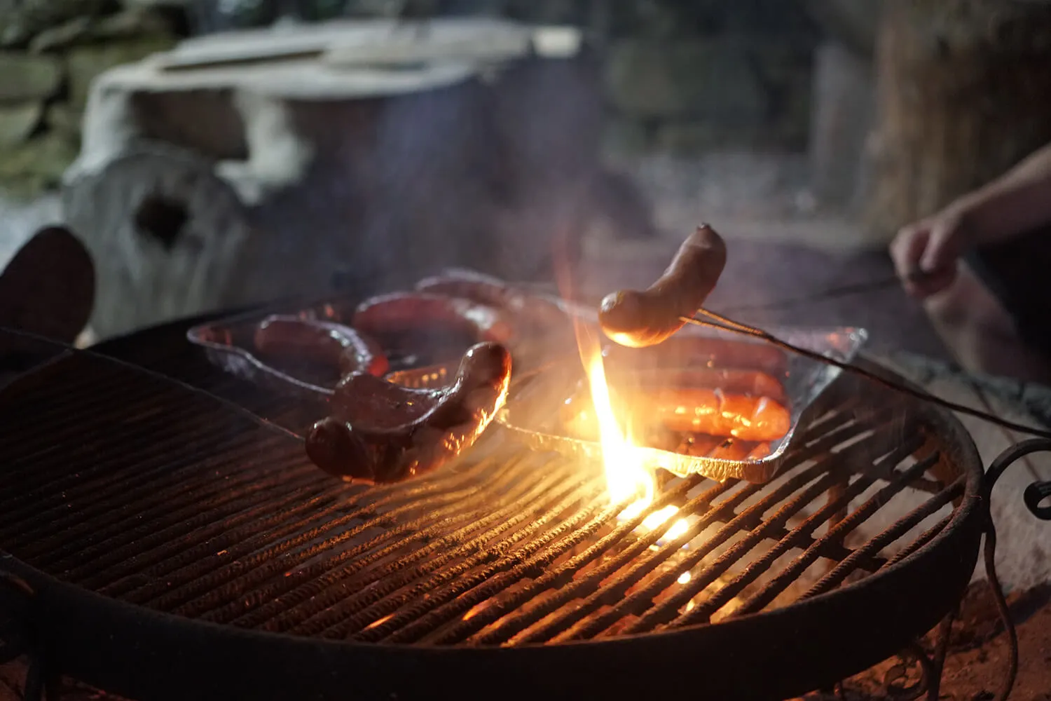 Sausages grilling over a campfire